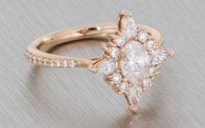 Oval diamond ballerina ring set with an array of pear shapes and round brilliant diamond around the centre stone